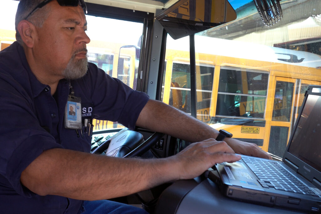 School bus technician reading can bus data on a laptop